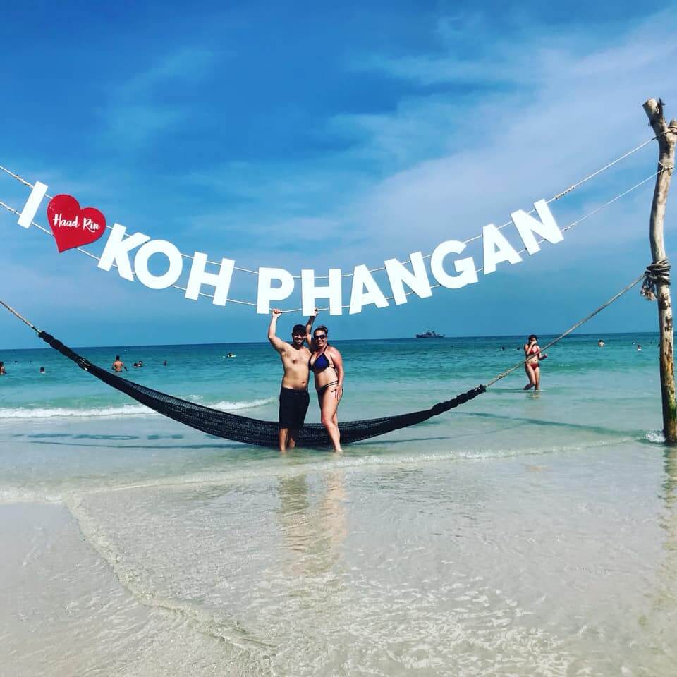 Bridget Rice and David Lesnieski standing under the I love Koh Phangan sign at Haad Rin Beach in Thailand.